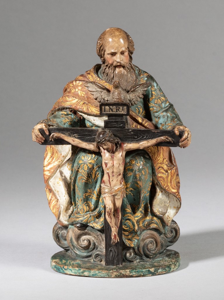 saint François d’Assise agenouillé devant le Christ en croix dans un paysage vallonné avec ville à l’arrière-plan et ciel étoilé