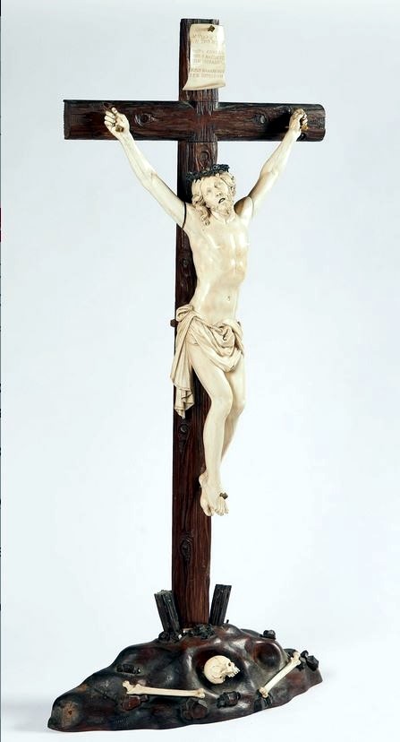 Exceptionnel crucifix en ivoire. La croix en chêne verni repose sur un tertre présentant des ossements et des instruments de la passion