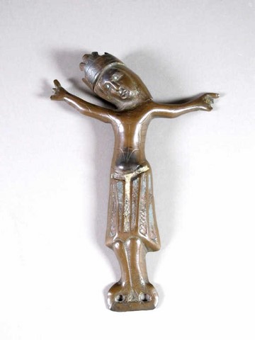 Christ d'applique d'une croix en cuivre repoussé, périzonium champlevé avec traces d'émail bleu, les yeux sont piqués d'une goutte d'émail bleu. Oeuvre de Limoges, milieu du XIIIe siècle